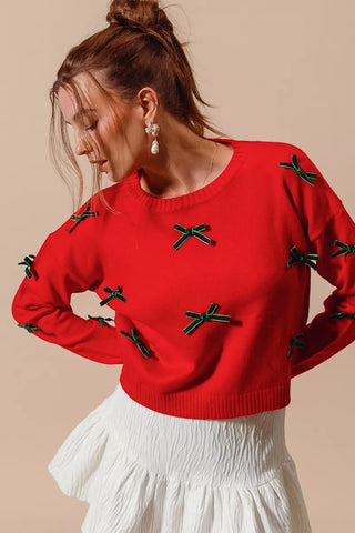 Front view of the SO ME red sweater decorated with small hunter-green ribbon bows.