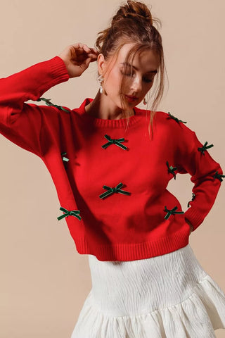 Front detail of the SO ME red sweater with green ribbon bows and ribbed round neckline.