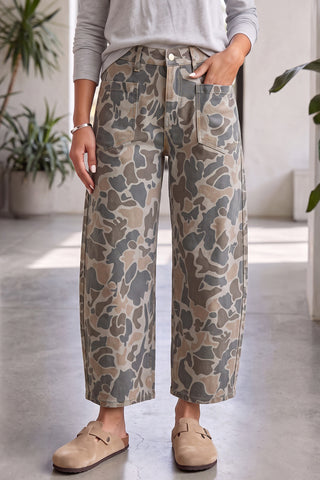 Front view of multicolour camouflage ankle-length jeans with large patch pockets, worn with a grey top and clogs.