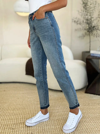 Side view of Judy Blue 88818 medium-wash release-hem jeans, worn with white sneakers.