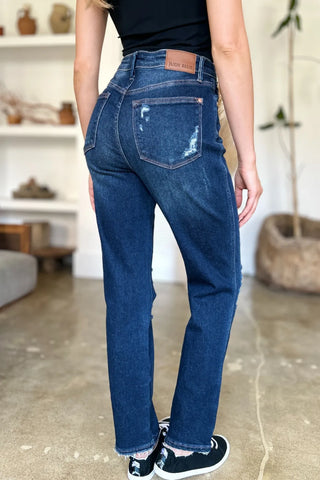 Rear three-quarter view of Judy Blue 88819 jeans with a distressed pocket and frayed ankle hems.