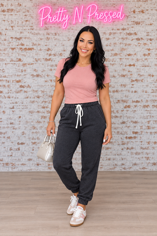 Natalie modeling Feeling Cozy ash-black acid-wash fleece sweatpants with white drawcord and elastic ankle cuffs.