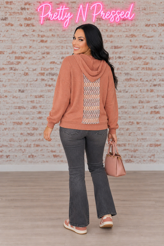 Natalie modeling the back of the Wave Hello rust hoodie, showing the narrow multicolor center panel and draped hood.