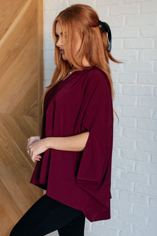 Wine Universal Philosophy poncho-style blouse, side view showing the loose silhouette.