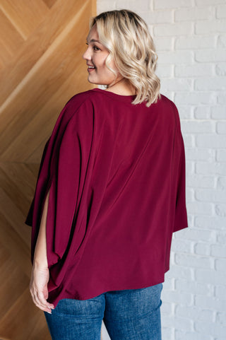 Wine Universal Philosophy poncho-style blouse, back view with jeans.