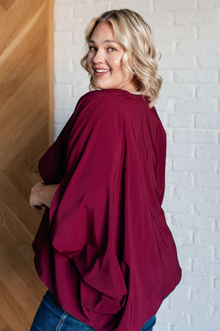 Wine Universal Philosophy poncho-style blouse, rear three-quarter view of the draped sleeve.
