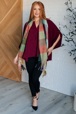 Wine Universal Philosophy poncho-style blouse, styled with a plaid scarf and black trousers.
