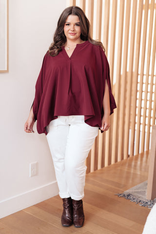 Wine Universal Philosophy poncho-style blouse, styled with white trousers and brown boots.