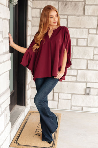 Wine Universal Philosophy poncho-style blouse, full outfit with flared jeans.