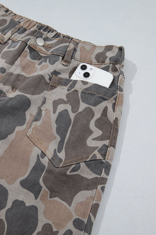 Close-up of a smartphone partially inside the camouflage jeans' front patch pocket.