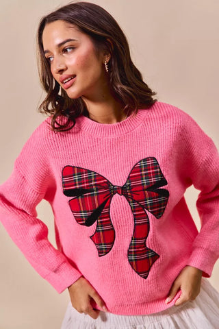 Front view of the SO ME pink plaid-bow sweater, styled with a white skirt.
