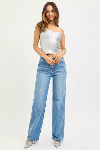Full outfit view of RISEN slouchy straight jeans styled with a silver top and pointed shoes.