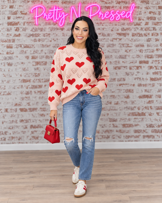 Natalie modeling the A Love Note Heart Sweater with distressed straight jeans and cream and red sneakers