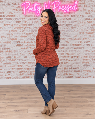 Natalie modeling the rust marled cowl neck pocketed top, rear three-quarter view