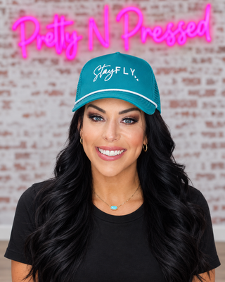 Natalie wearing the teal Stay Fly trucker hat at Pretty N Pressed Boutique